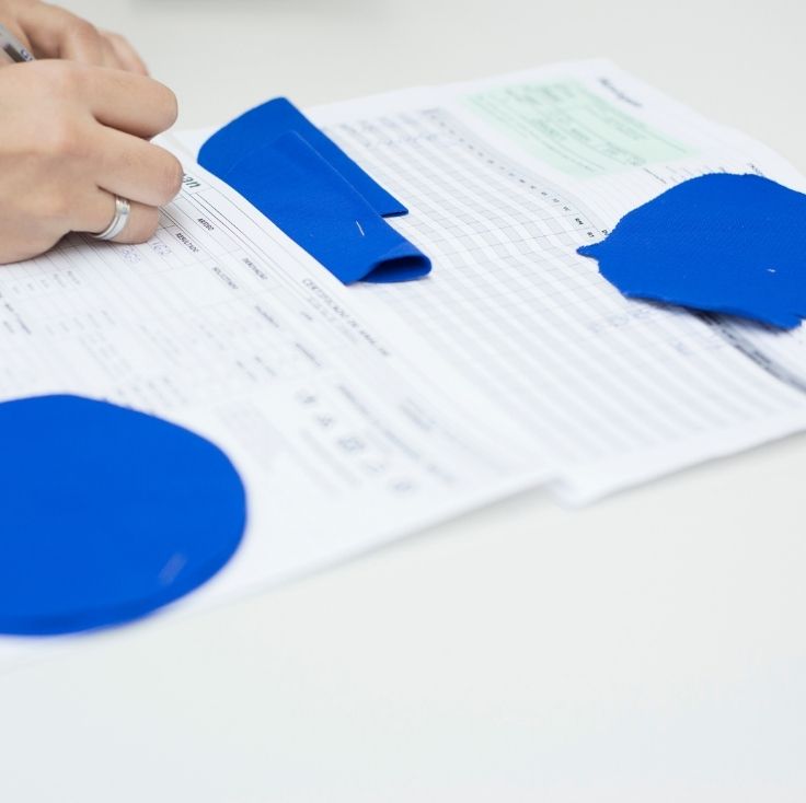 Amostras de tecido azul sobre uma ficha de análise, enquanto uma pessoa registra informações do teste.